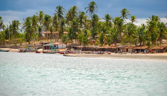 Jericoacoara massive sand dunes meeting turquoise lagoons with kitesurfers in the background